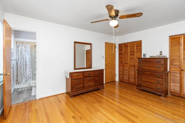 a view of empty room with wooden floor and fan