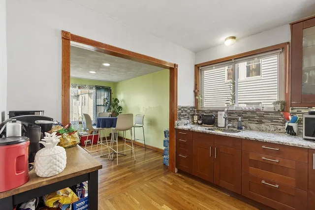 a dining hall with stainless steel appliances granite countertop a stove a sink dishwasher and cabinets with wooden floor