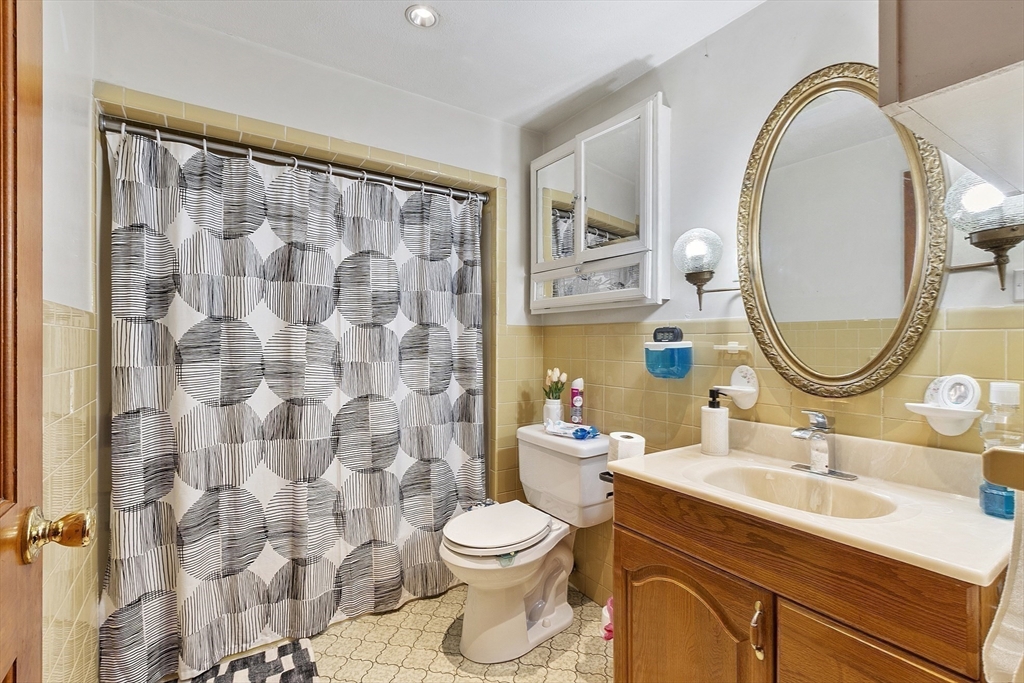 483 Broadway, Unit 1 Medford, MA 02155 - Photo 8 of 13 a bathroom with a sink a mirror a toilet and a mirror