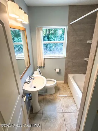 a bathroom with a sink a toilet a mirror and bathtub