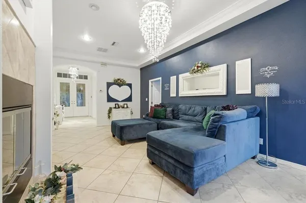 a living room with furniture large windows and a chandelier