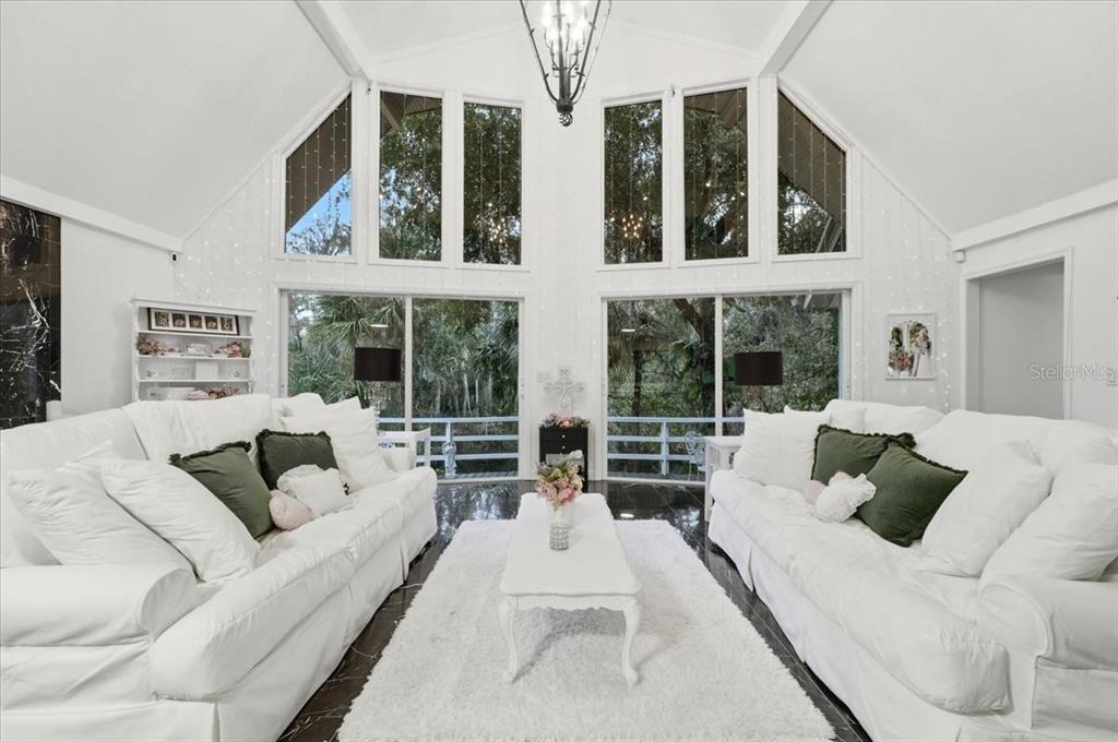 4703 Rambling River Road Brandon, FL 33511 - Photo 22 of 62 a living room with furniture large windows and a chandelier