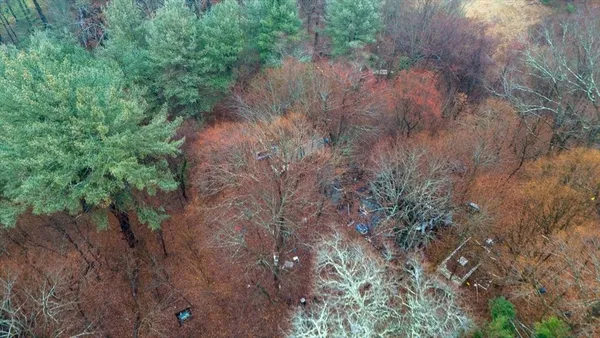 an aerial view of residential house with outdoor space and trees all around