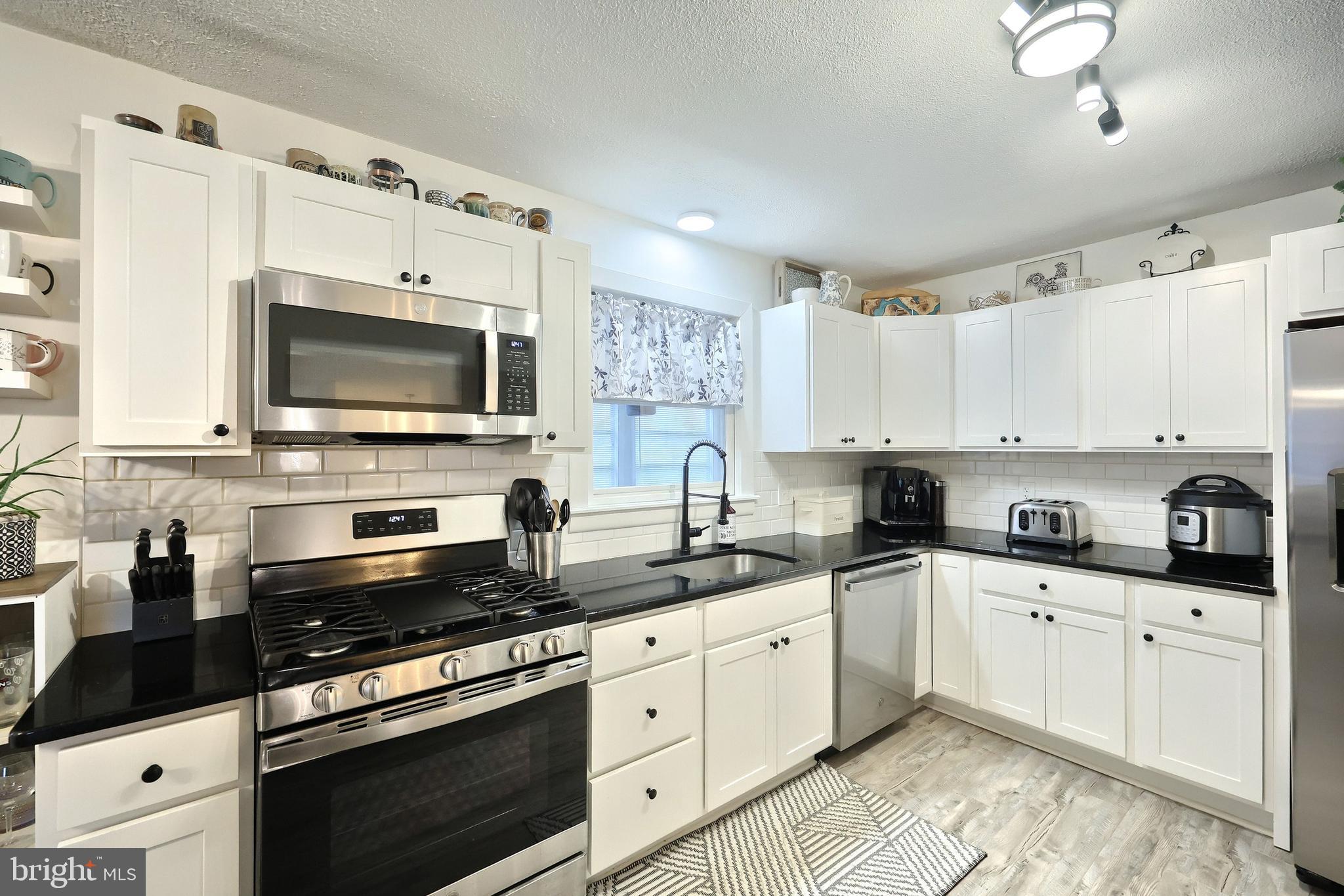 56 York Road York, PA 17407 - Photo 10 of 45 a kitchen with stainless steel appliances white cabinets a sink a stove a microwave and wooden floors
