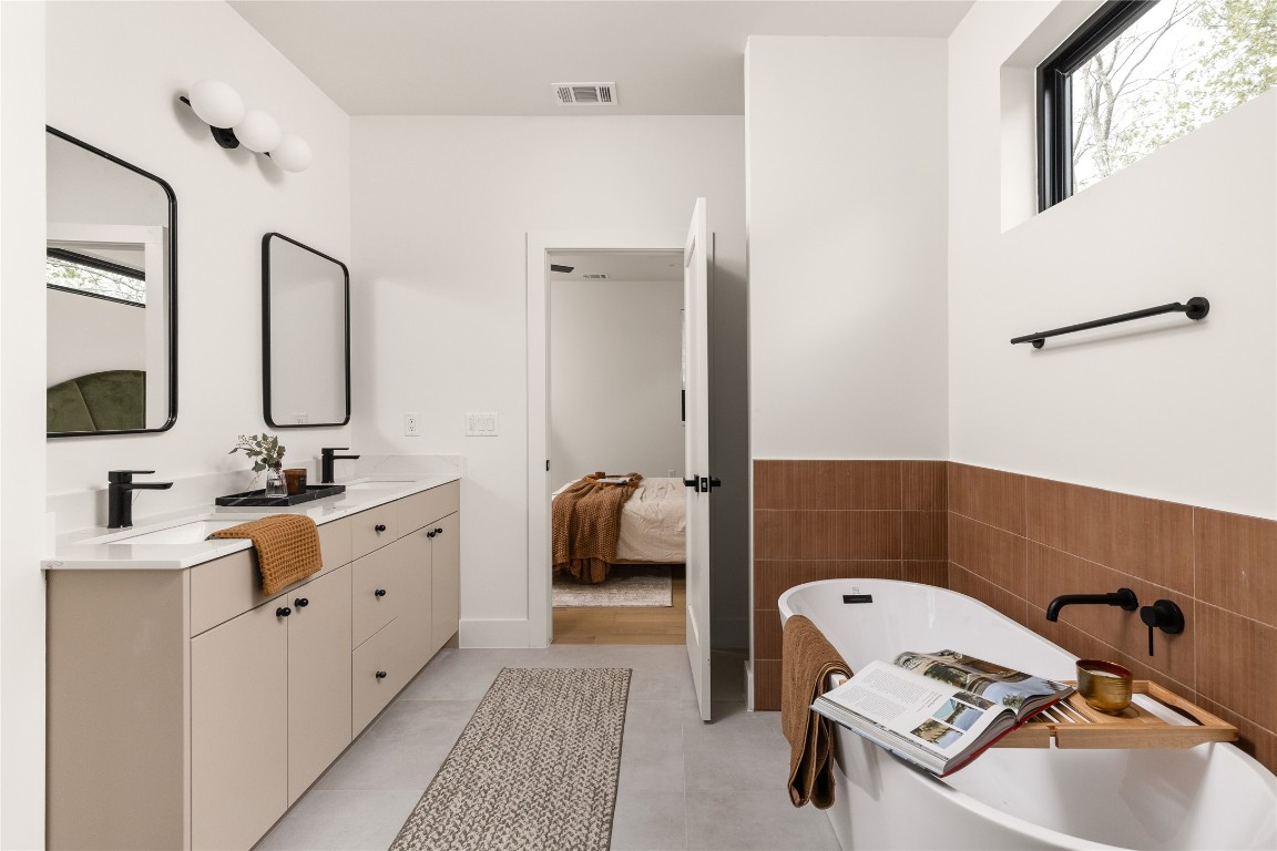 4416 South 1st Street, Unit 2 Austin, TX 78745 - Photo 22 of 40 Bathroom with healthy amount of natural light, connected bathroom, double vanity, a soaking tub, and tile walls