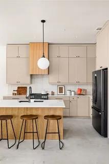 a kitchen with kitchen island a stove a sink a refrigerator with a dining table and chairs