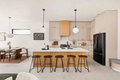 a kitchen with stainless steel appliances kitchen island granite countertop a dining table chairs and white cabinets