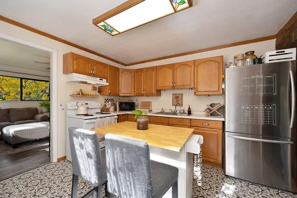 a kitchen with stainless steel appliances a refrigerator a stove a sink a dining table and chairs with wooden floor