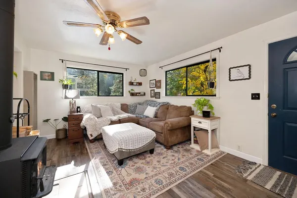 a living room with furniture two large window and a flat screen tv