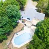 an aerial view of a house with a yard and trees all around
