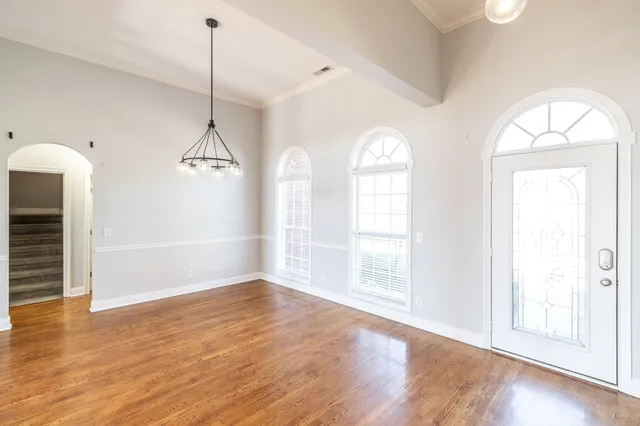 a view of an empty room with wooden floor fireplace and a window