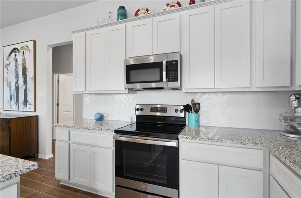 a kitchen with white cabinets and black appliances