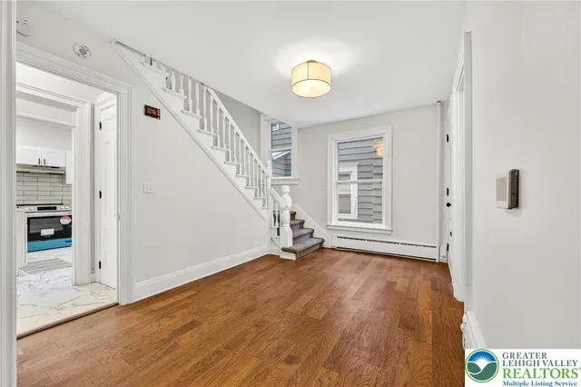 a view of an empty room with window and wooden floor