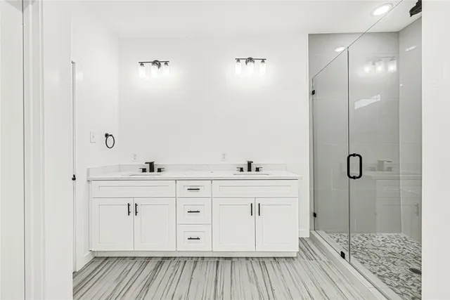 a spacious bathroom with a double vanity sink a mirror and shower