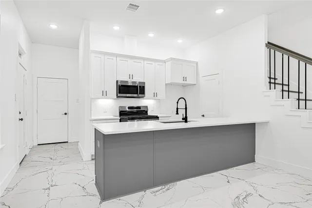 a kitchen with a sink a microwave and cabinets