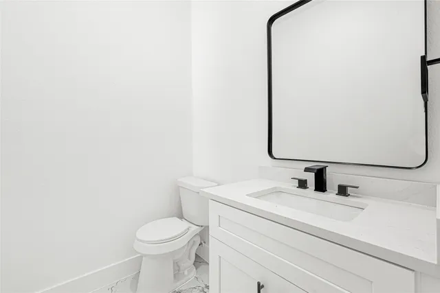 a bathroom with a sink vanity mirror and toilet