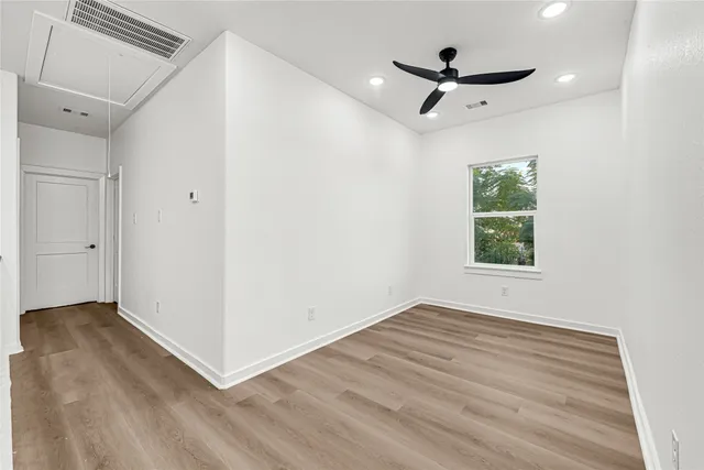 an empty room with wooden floor and ceiling fan