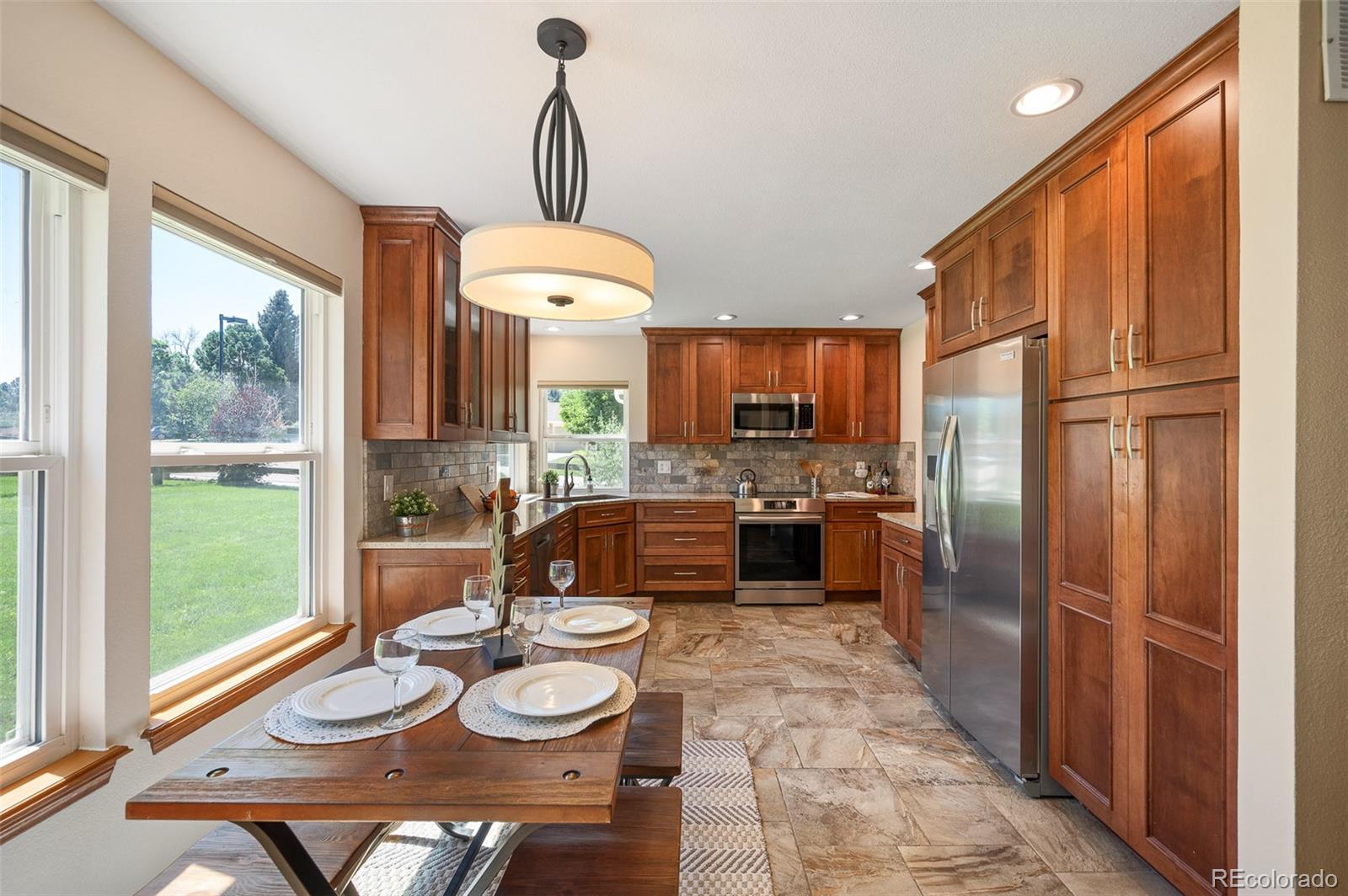 7412 Berkeley Court Castle Pines, CO 80108 - Photo 7 of 37 a kitchen with a refrigerator a stove a sink and a dining table with wooden floor