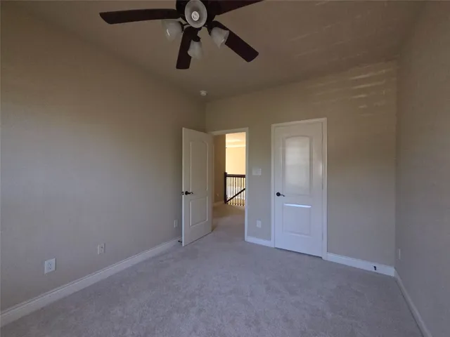 a view of an empty room and chandelier fan