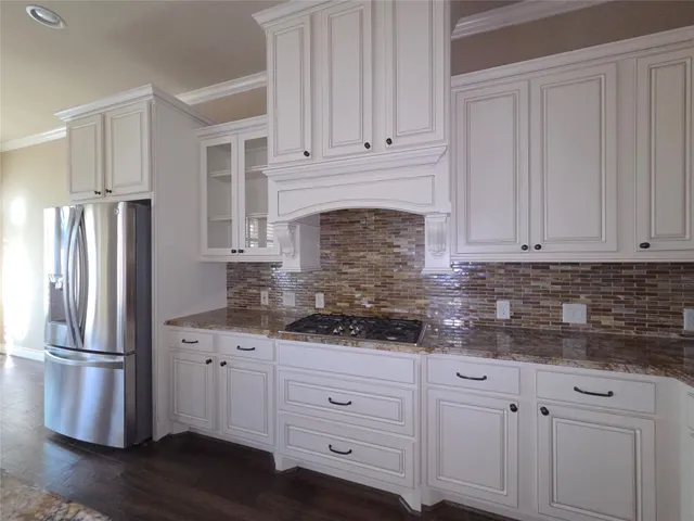 a kitchen with stainless steel appliances granite countertop a refrigerator sink and white cabinets