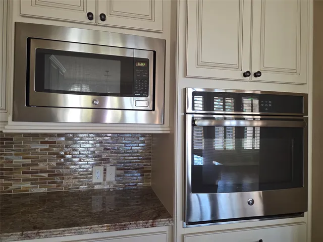 a kitchen with granite countertop white cabinets and stainless steel appliances