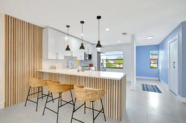 a kitchen with stainless steel appliances kitchen island granite countertop a table chairs in it and wooden floors