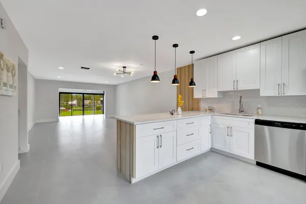 a large kitchen with granite countertop a window and white cabinets