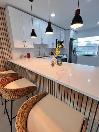 a kitchen with stainless steel appliances granite countertop a stove a refrigerator a sink a dining table and chairs with wooden floor