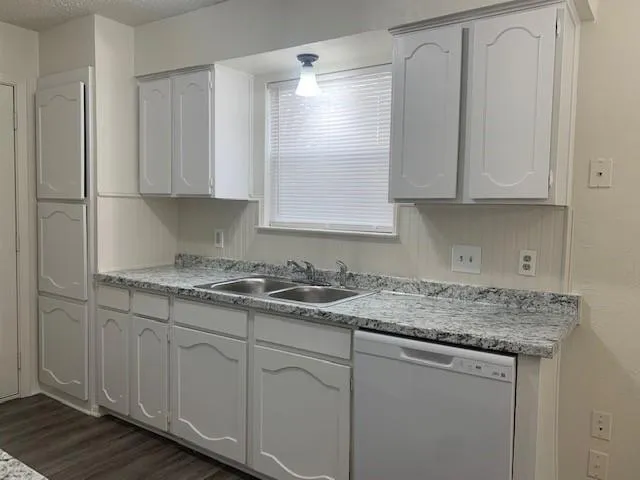 a kitchen with granite countertop white cabinets and a sink
