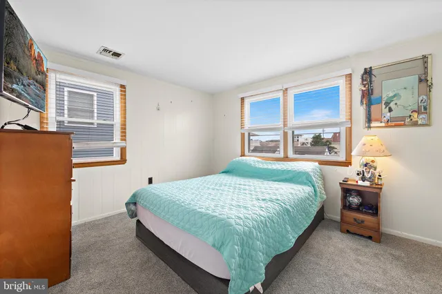 a bedroom with a bed and a flat tv screen on dresser