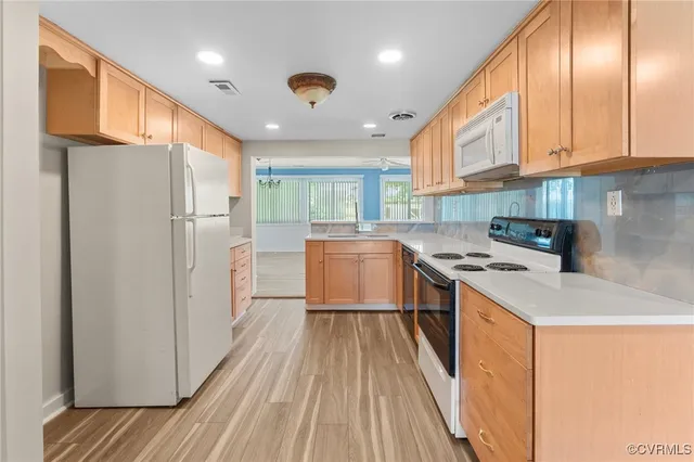 a kitchen with a refrigerator a sink and dishwasher with wooden floor