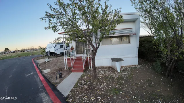 a view of a white house with a yard and tree s