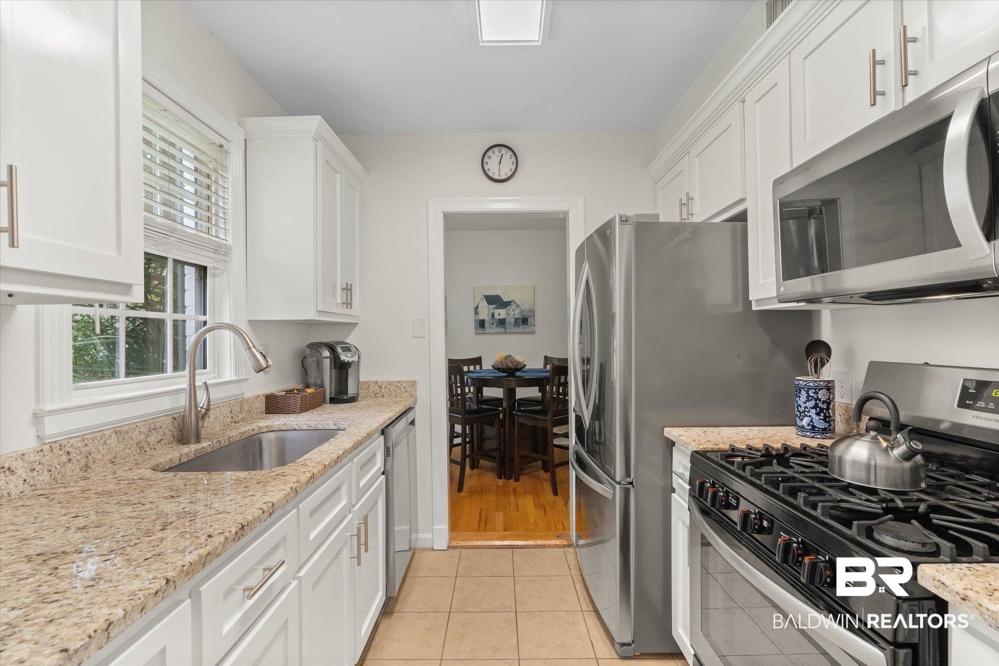 214 Upham Street, Unit 18A Mobile, AL 36607 - Photo 10 of 29 Kitchen featuring appliances with stainless steel finishes, white cabinetry, light tile patterned floors, and light stone countertops