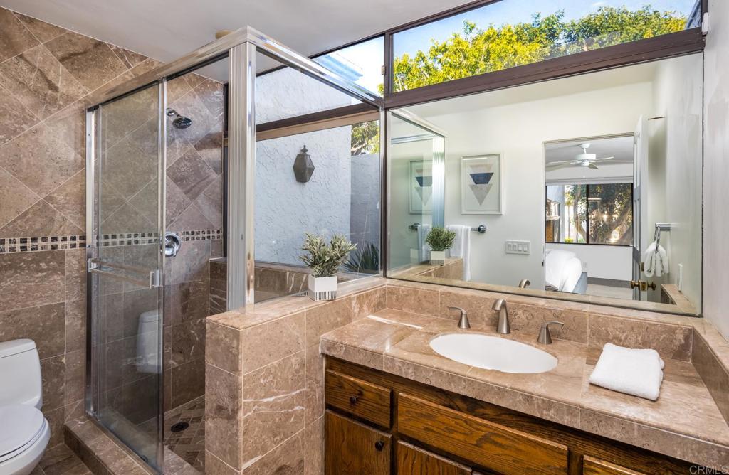 7157 Obelisco Circle Carlsbad, CA 92009 - Photo 30 of 44 a bathroom with a granite countertop sink a toilet a mirror and shower
