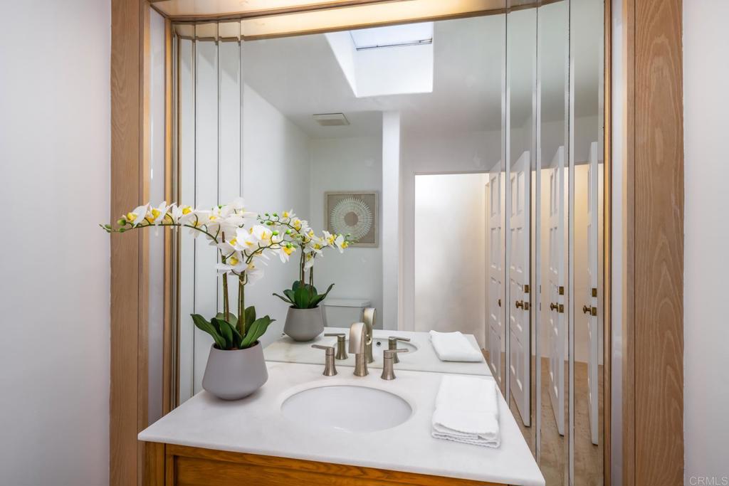 7157 Obelisco Circle Carlsbad, CA 92009 - Photo 33 of 44 a bathroom with a sink a mirror and a potted plant