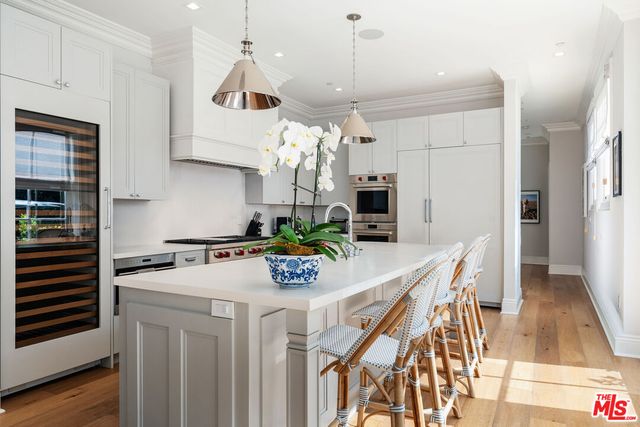 a large kitchen with a large counter top a sink and stainless steel appliances