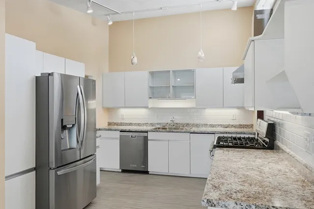 a kitchen with stainless steel appliances granite countertop a refrigerator a stove and a sink