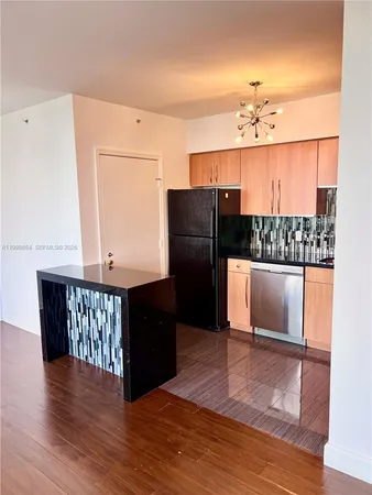 a kitchen with stainless steel appliances granite countertop a refrigerator a sink dishwasher and wooden cabinets with wooden floor