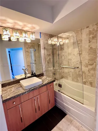 a bathroom with a granite countertop sink a mirror and a bathtub