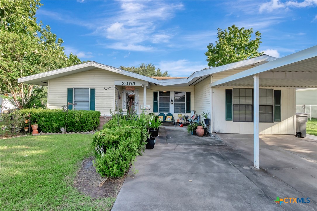 a view of a house with potted plants and a bench