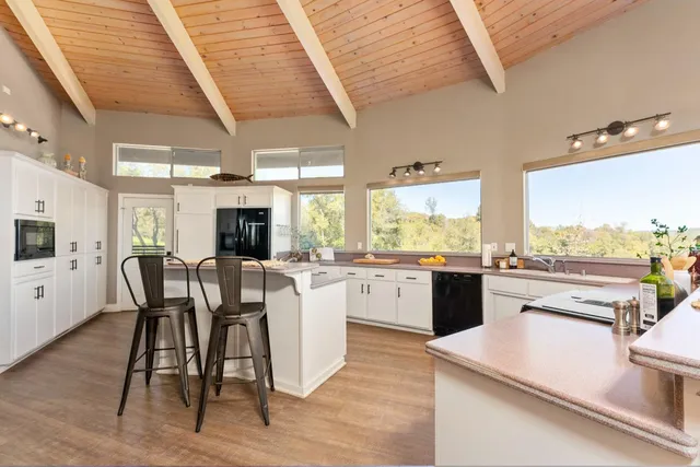 a kitchen with stainless steel appliances granite countertop a table chairs and a refrigerator