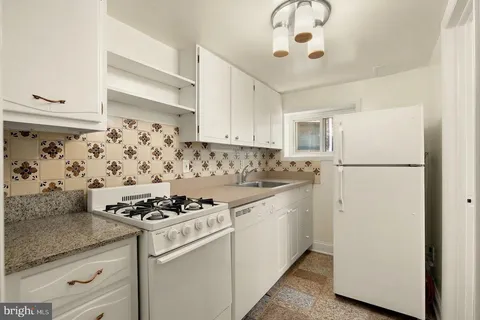 a kitchen with white cabinets and white appliances