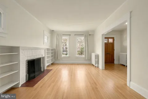 an empty room with wooden floor fireplace and windows