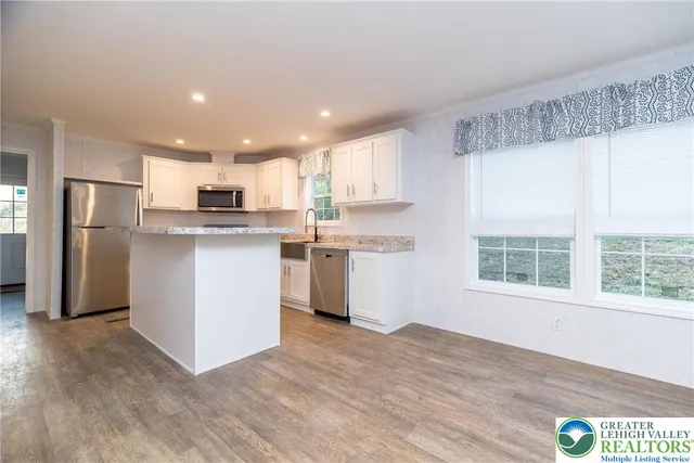 a kitchen with stainless steel appliances granite countertop a stove a refrigerator a sink a microwave oven with wooden floor and cabinets