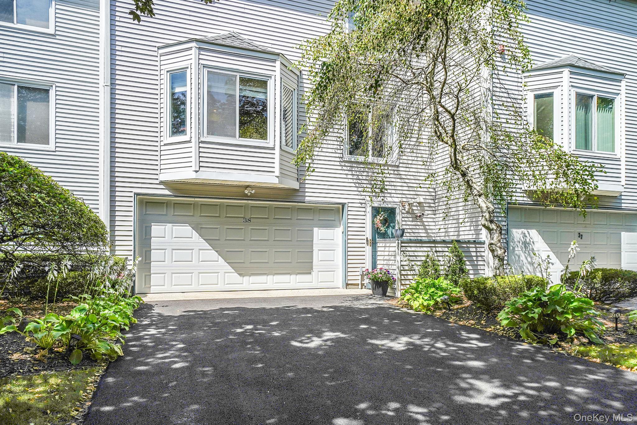 View of side of property featuring a garage and asphalt driveway