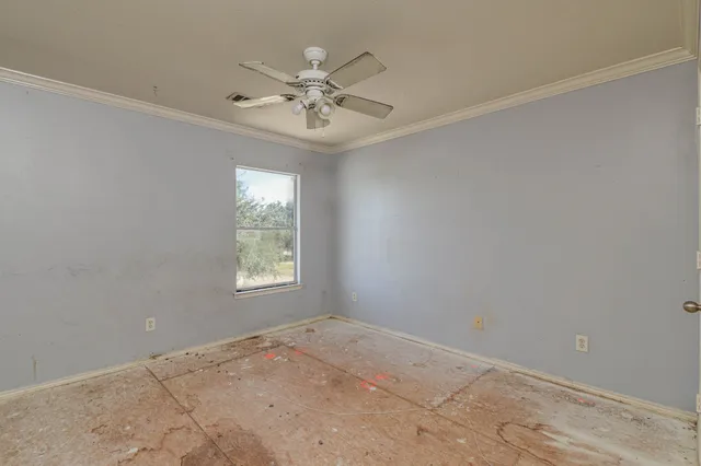 a view of an empty room and chandelier fan