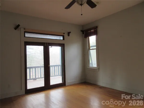an empty room with wooden floor and windows