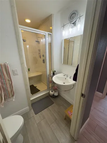 a bathroom with a sink a toilet a mirror and shower