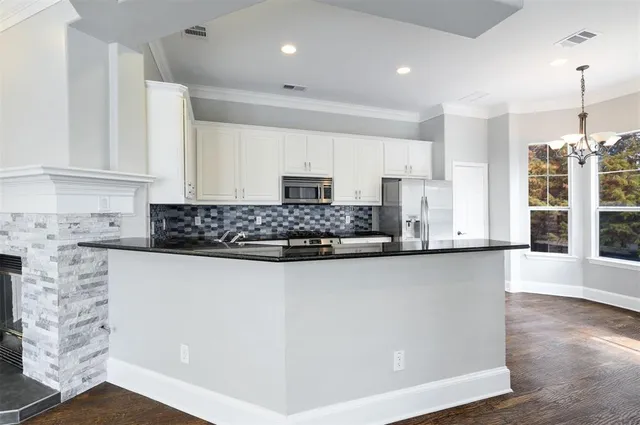 a kitchen with granite countertop a refrigerator sink and cabinets