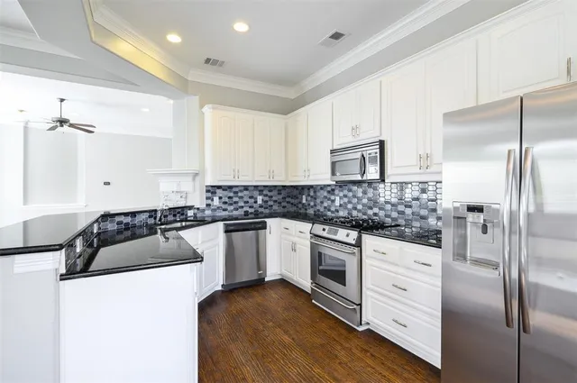 a kitchen with stainless steel appliances granite countertop a refrigerator a sink and wooden floors